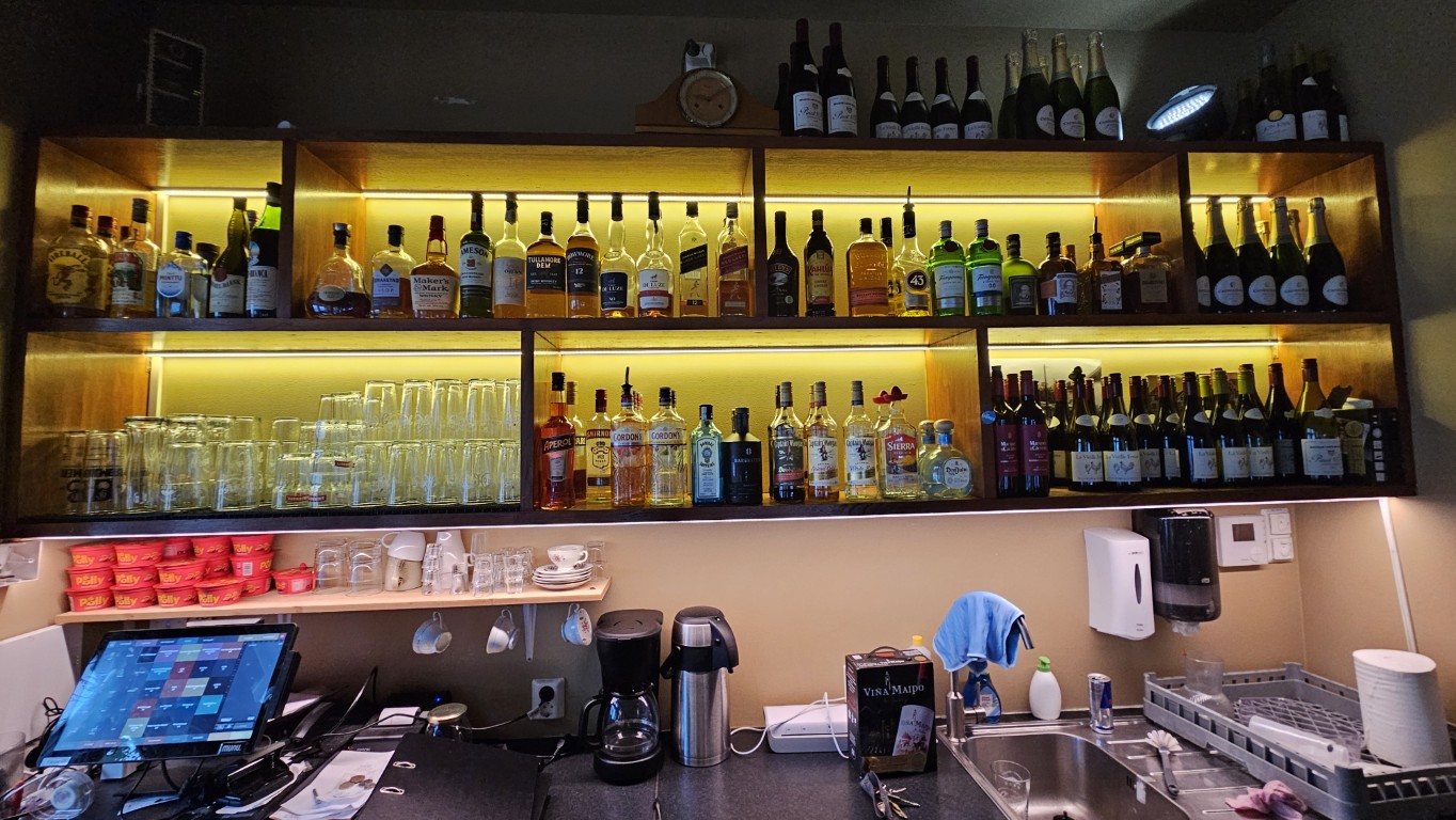 Backbar med øl, brennevin og vin på opplyste hyller